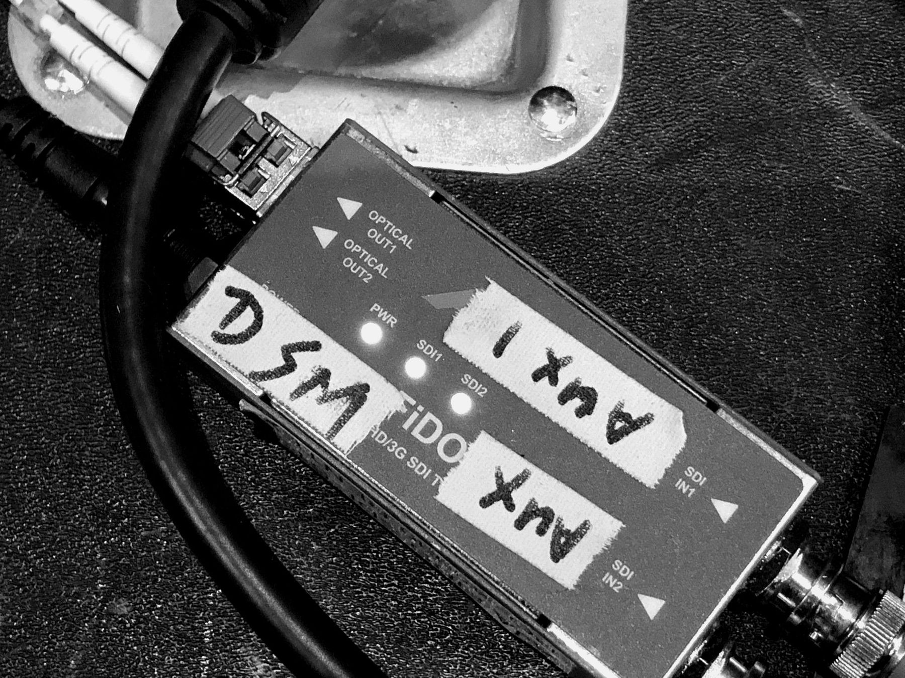 An SDI fibre transceiver labelled DSM and Aux 1 in gaffer tape.